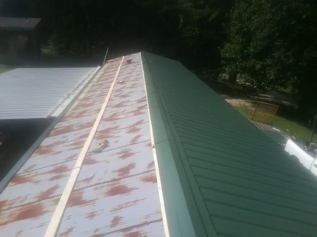 Old rusted panels beside newly installed green metal roofing — Wind Damage Roof Repair by Roofing Brothers in East Waterford