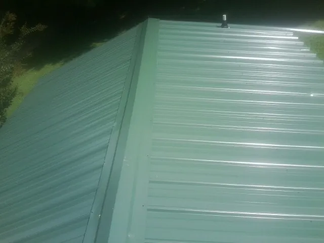New green metal panels meeting at the ridge of a roof — Flat Roof Repair work by our crew in East Waterford