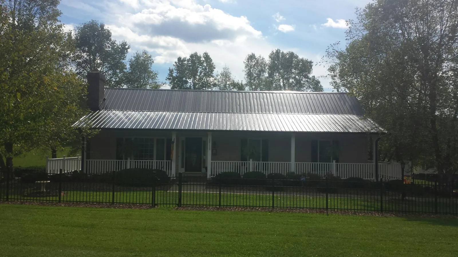 Gray metal roof on a brick ranch with a full width front porch — Gutter Guard Installation work by our crew in East Waterford