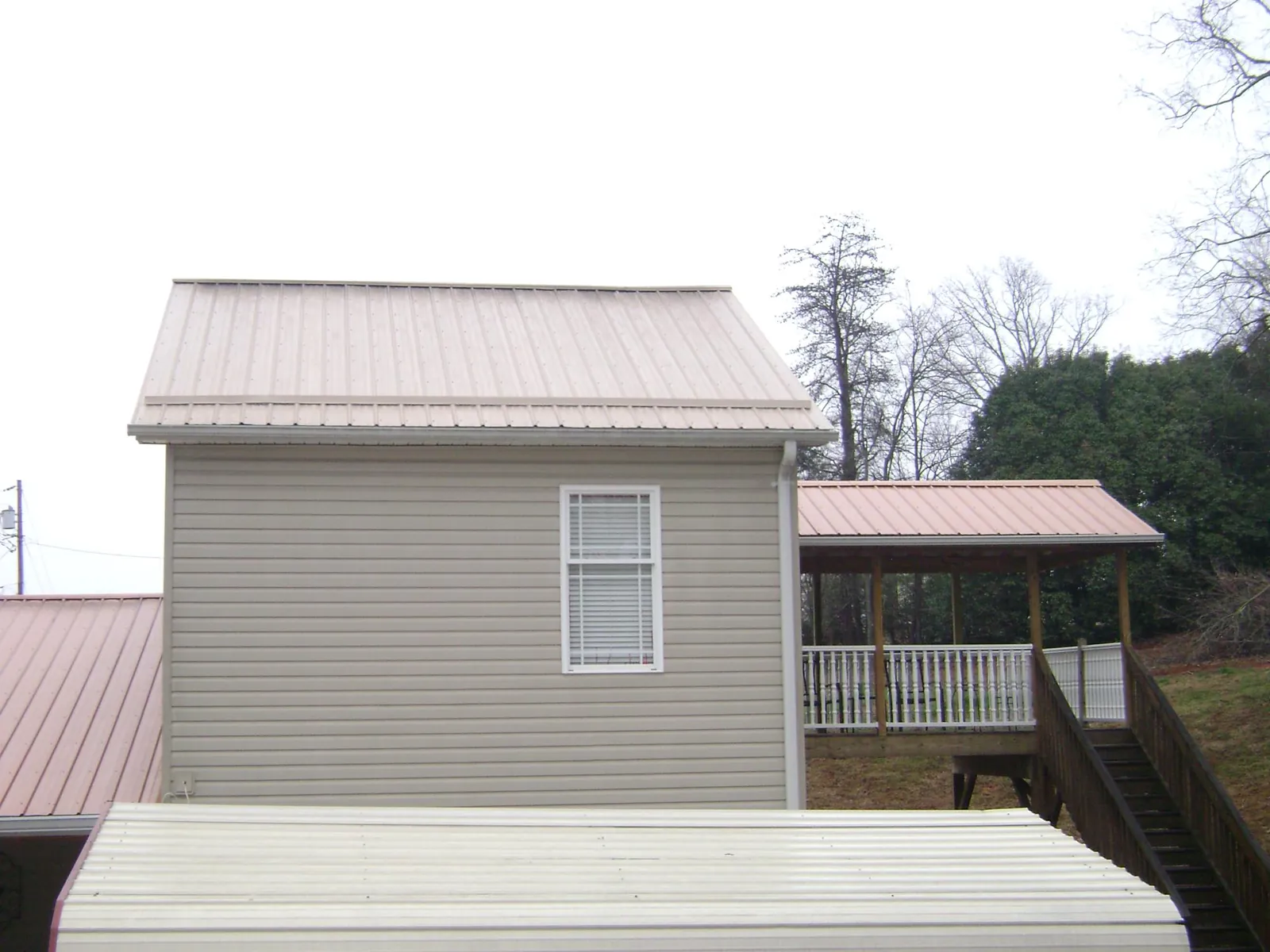 Tan metal roofs on a two story addition and attached porch, from a Roof Replacement job in East Waterford