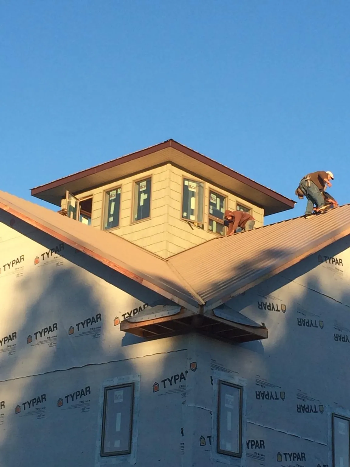 Roofers working around a rooftop cupola on a new metal roof at sunset — Roof Waterproofing in East Waterford by Roofing Brothers